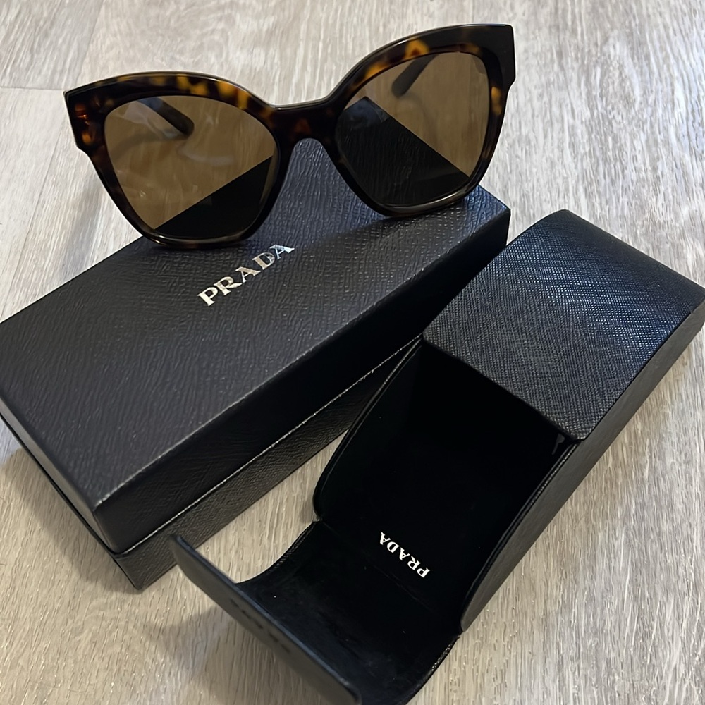 Prada oversized black sunglasses with cat-eye shape and warm brown lenses